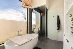 Bathroom featuring a freestanding bath, vanity, and dark tile patterned flooring