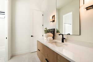 Bathroom with double vanity, light tile patterned floors, and a tub