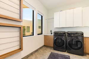 Laundry room featuring separate washer and dryer and cabinet space