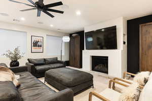 Living area featuring a fireplace with raised hearth, a ceiling fan, and recessed lighting