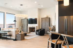 Living room with light wood-type flooring, a high end fireplace, and recessed lighting