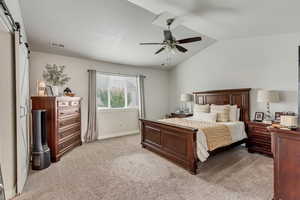 Bedroom featuring a barn door, light carpet, lofted ceiling, and ceiling fan