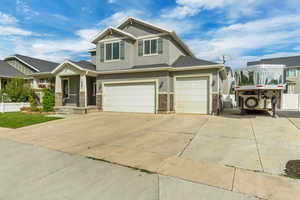 Craftsman-style home with stucco siding, driveway, stone siding, and a garage