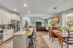 Kitchen featuring a kitchen bar, a kitchen island with sink, light wood-type flooring, open floor plan, and decorative light fixtures
