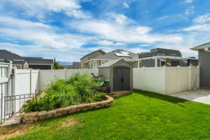 Fenced backyard featuring a storage unit