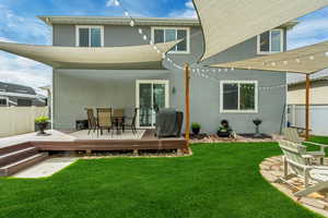 Rear view of house with stucco siding, outdoor dining space, and a deck