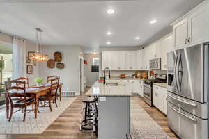 Kitchen with appliances with stainless steel finishes, light stone countertops, white cabinetry, dark wood-type flooring, and recessed lighting