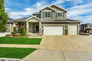Craftsman-style home featuring stucco siding, driveway, stone siding, covered porch, and an attached garage