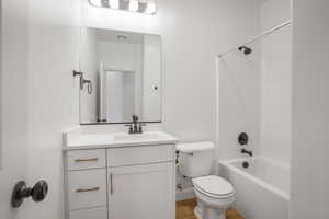 Full bathroom with tub / shower combination, vanity, and light wood-style floors
