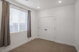 Unfurnished bedroom featuring carpet flooring, a closet, and recessed lighting