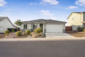 Prairie-style home with stone siding, stucco siding, concrete driveway, an attached garage, and a tile roof
