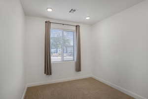 Carpeted spare room featuring baseboards and recessed lighting
