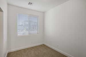 Carpeted spare room featuring baseboards