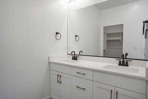 Full bathroom with double vanity and a walk in closet
