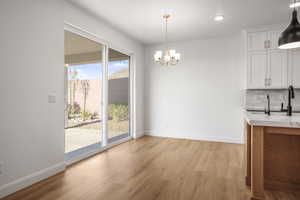 Unfurnished dining area with light wood finished floors, a chandelier, and recessed lighting
