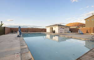 Community pool with a mountain view, a fenced backyard, and a patio area