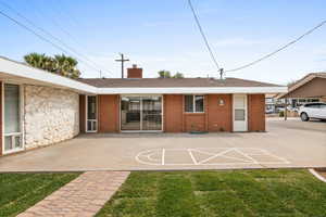 Rear view of house with a chimney, a yard, brick siding, and roof with shingles