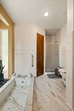 Bathroom with tile walls, a stall shower, and light marble finish floors