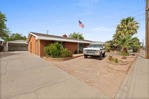 Single story home with an outbuilding, a chimney, brick siding, and a detached garage