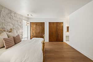Bedroom with multiple closets, wood finished floors, and ensuite bath