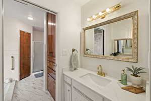 Full bath featuring vanity and light marble finish floors
