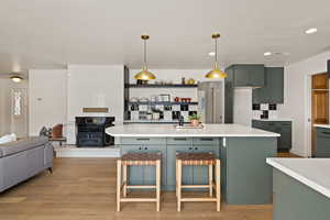 Kitchen with green cabinets, open floor plan, decorative light fixtures, light wood-style floors, and recessed lighting