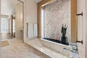 Bathroom with marble look tile flooring and tile walls