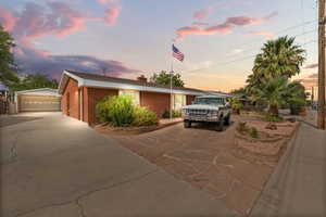 View of front of property featuring brick siding, an outdoor structure, a detached garage, and a chimney