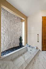 Bathroom featuring tile walls and marble look tile flooring