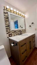 Bathroom featuring backsplash, vanity, and dark wood finished floors