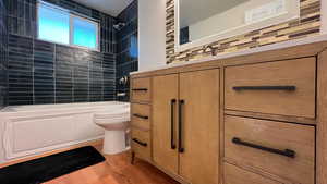 Bathroom with tub / shower combination, vanity, and light wood-type flooring