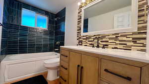 Bathroom with shower / tub combination, vanity, backsplash, and light wood-style flooring