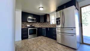 Kitchen with appliances with stainless steel finishes, dark cabinetry, and decorative backsplash