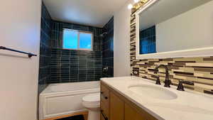 Bathroom featuring shower / washtub combination, vanity, and backsplash