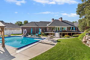 View of swimming pool featuring a water slide, a patio area, a diving board, and stairs.