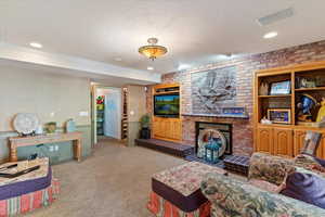 Living area featuring a textured ceiling, carpet, a brick fireplace, brick wall, and recessed lighting