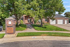 Obstructed view of property with brick siding, a garage, concrete driveway, french doors, and a front yard