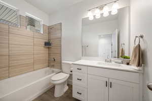 Full primary bathroom with shower / washtub combination, vanity, and dark wood-type flooring