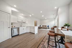 Kitchen featuring white cabinetry, recessed lighting, light countertops, stainless steel dishwasher, and a peninsula