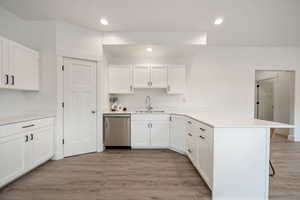 Kitchen with white cabinets, recessed lighting, a peninsula, dishwasher, and light wood finished floors
