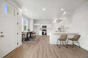 Kitchen with a breakfast bar area, light countertops, white cabinets, a peninsula, and stainless steel appliances
