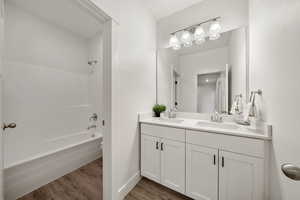 Full Bathroom with shower / washtub combination, dark wood-style floors, and double vanity