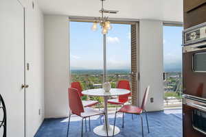 Carpeted dining room featuring a wall of windows and a chandelier