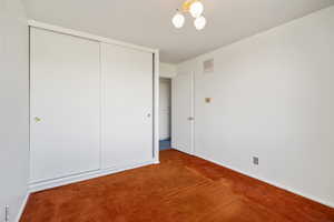 Unfurnished bedroom featuring a closet, a chandelier, and carpet flooring