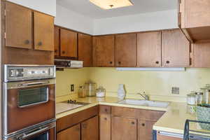 Kitchen featuring brown cabinets, light countertops, black electric stovetop, and extractor fan