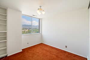 Empty room with a mountain view, a chandelier, and carpet floors