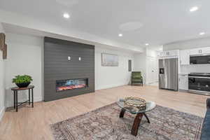 Living room featuring light wood-style flooring, recessed lighting, and a large fireplace