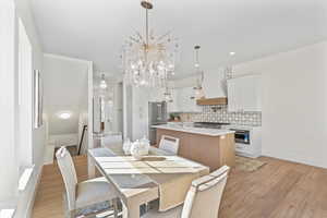 Dining room with light wood finished floors, a chandelier, and recessed lighting