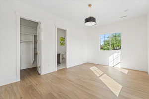 Unfurnished bedroom with light wood finished floors, a walk in closet, and connected bathroom