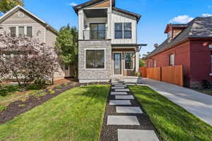 View of front of property with board and batten siding, a balcony, and stone siding